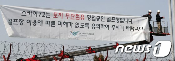인천공항공사 관계자가 인천시 중구 스카이72 하늘 코스 앞 도로변에 현수막을 걸고 있다.
